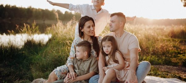 A family of five enjoying a serene picnic in a sunlit meadow during sunset.